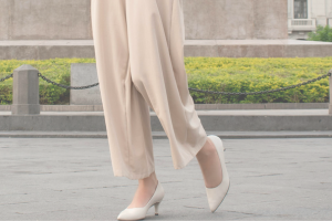 白い長ズボンと白いパンプスを履いた女性の足